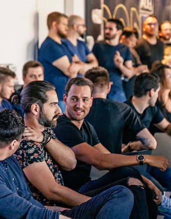 Eine Gruppe an Mitarbeitenden sitzen nebeneinander und diskutieren.