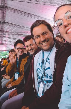 Eine Gruppe Mitarbeitender sitzen im Publikum bei einem Event.